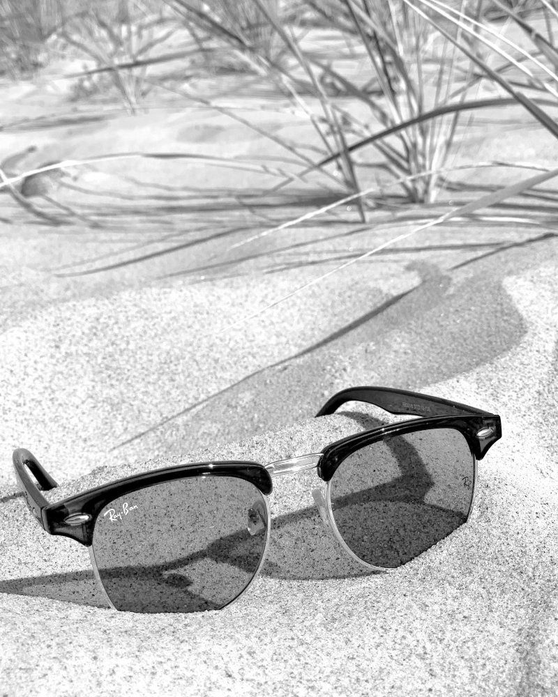 lunettes solaires Ray-Ban posées sur le sable d'une dune